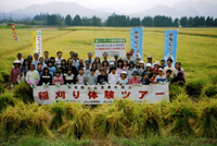 参加者全員で記念写真。手前は刈取った稲の三束立て